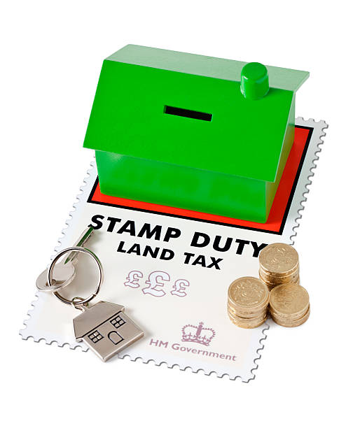 Green house money box on top of a Stamp Duty Land Tax form with money and a house key